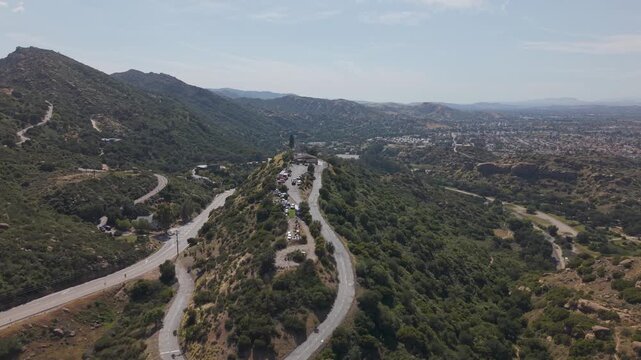 Scenic mountain landscape of Simi Valley California with winding road and cars driving along green hills near Santa Susana Pass under blue sky with expansive valley. Aerial establishing wide shot.