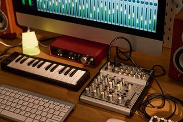 Close up of music production workstation showing computer audio mixer, MIDI keyboard, sound interface, studio controls. Supporting podcast editing, recording, sound design marketing © pressmaster