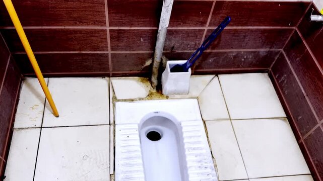 Traditional Indian squat toilet and ceramic floor pan seat in bathroom washroom interior showing hygienic sanitation design in household restroom setting