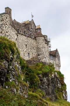 View of Duart Castle with its historic stone walls and turrets perched on a rocky cliff with green vegetation in Isle of Mull, Scotland, United Kingdom.