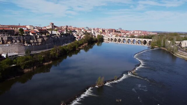 Spectacular 4K drone overflight of the ancient city of Zamora, Spain, along the Duero River. Capture medieval walls, cathedral, castle, and stone bridge with beautiful water reflections.