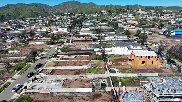 Homes burned in the January 2025 Palisades wildfire with scorched lots and new home construction in the California foothills - forward aerial flyover