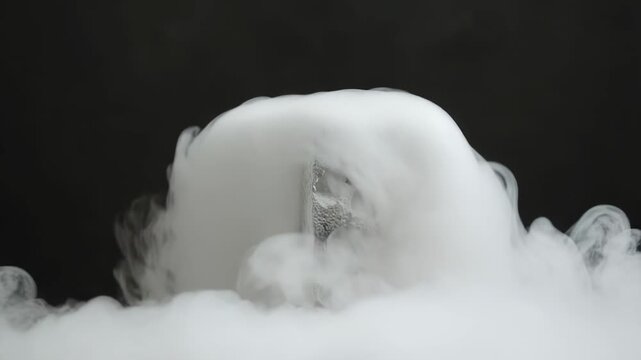 Porous, gray block on a rough surface generating white vapor during a chemical reaction or scientific experiment, creating a visual display of atmospheric effects