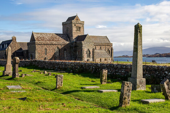 View of Iona Abbey and Nunnery with ancient stone crosses in the graveyard and the sea in the background Isle of Iona, Scotland, United Kingdom.