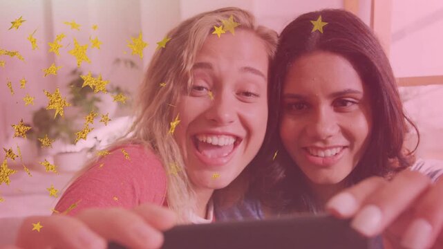 Two women angling phone taking social selfie while leaning, gold-star filter drifting over faces