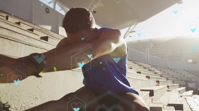 Male athlete reaching on bleachers, wringing towel and preparing fitness, with floating blue hearts