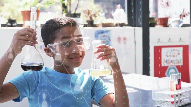 Boy holding two flasks in science lab, tilting right flask, causing animated icons linking lines