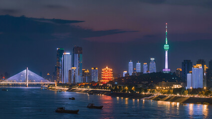 Fototapeta premium Wuhan cityscape at twilight with iconic bridge, illuminated skyline, and river view