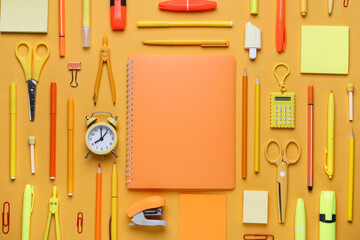 Different school stationery supplies and alarm clock on orange background © Pixel-Shot
