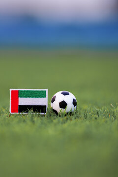 United Arab Emirates flag patch beside classic soccer ball on green football field, representing global competition, national pride, and modern Middle East sports identity.