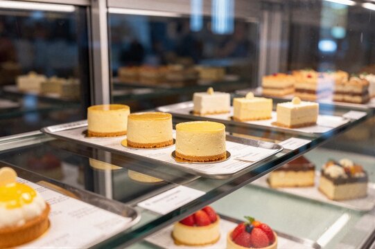 Assorted gourmet cheesecakes and fruit tarts in bakery display fridge for pastry shop menu and sweet dessert marketing