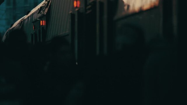 Train arrives at station while people wait in the evening light near the city