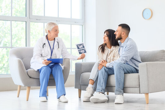Female fertility doctor showing sonogram image to couple after IVF in clinic