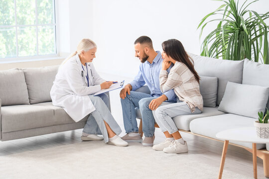 Female fertility doctor advising young couple on IVF in clinic