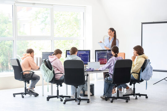 Female teacher conducting lesson to students at school computer lab
