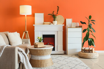 Obraz premium Fireplace with sofa, commode and glowing lamp near orange wall in living room