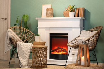 Obraz premium Fireplace with armchairs, glowing candle and coffee table near turquoise wall in living room