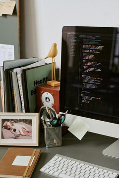 Vertical shot of developer workstation displaying programming code on desktop monitor, organizing digital project workflow. Suitable for software development, tech business, remote work content