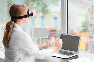 Female doctor using VR glasses with controllers at table in clinic © Pixel-Shot