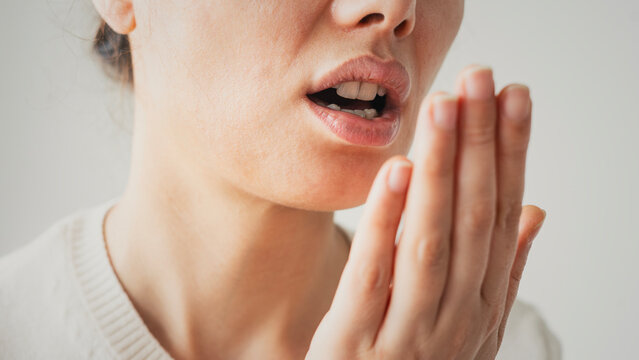 Woman is checking smell of breath