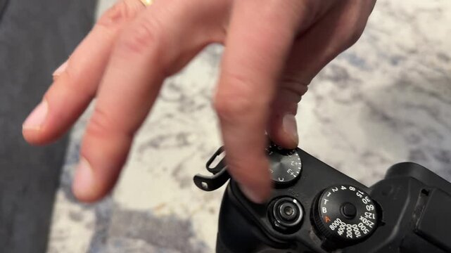 Hand adjusting control dial on digital camera top panel, photography settings change and creative equipment concept
