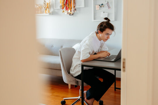 Focused young person working on laptop at home