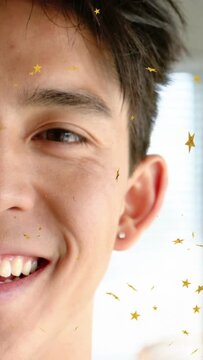 Vertical video: Man smiling, tilting in home, smile making stars drifting on cheek with stud for ad
