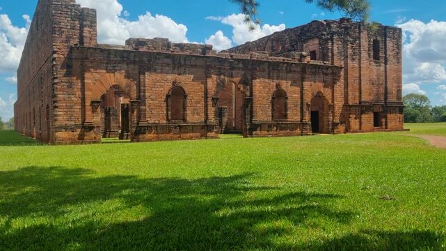 Ruins of the Jesuit mission Jes&uacute;s de Tavarang&uuml;&eacute; in Paraguay on a sunny summer day, with green grass in front of the historic brick structure under a clear blue sky, showcasing cultural heritage