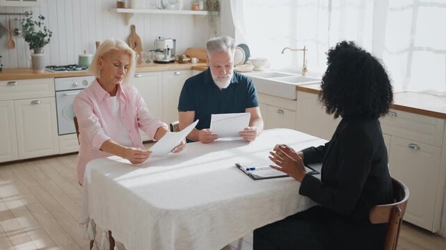 Female insurance agent consulting senior people about insurance property program . Elderly spouses thinking about buying new house or automobile with bank credit, meeting with professional lawyer