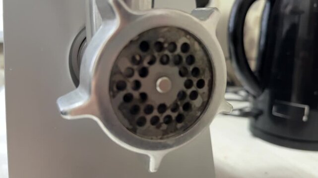 meat grinder operating in close up, kitchen appliance actively mincing food during cooking preparation