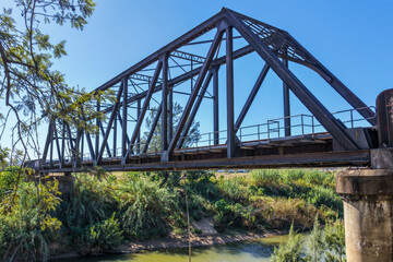 Fototapeta premium Aerial side view of the Paterson railway bridge spanning the Hunter River in New South Wales Australia. Drone photograph captures the historic rail bridge alongside the river.