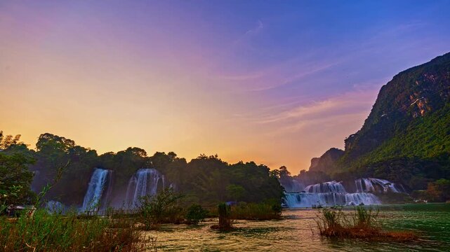 Traditional mountain life unfolds near Ban Gioc Falls as locals work the rice fields by hand, creating an authentic countryside atmosphere beneath the powerful waterfall.
