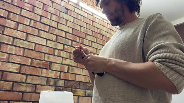 Man selecting and adjusting screwdriver bit, tool setup and preparation concept, choosing correct attachment for repair work indoors