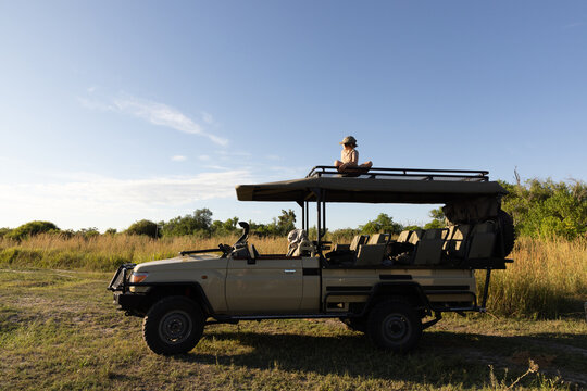 smiling young boy on hood of safari vehicle, Okavango Delta, Botswana, Africa