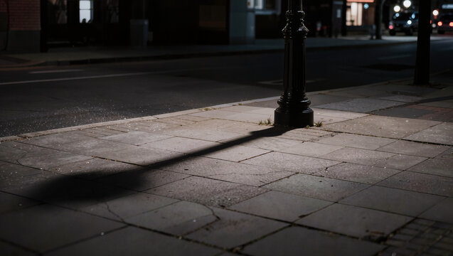 Street Lamp Casting Long Shadow on Sidewalk at Dusk