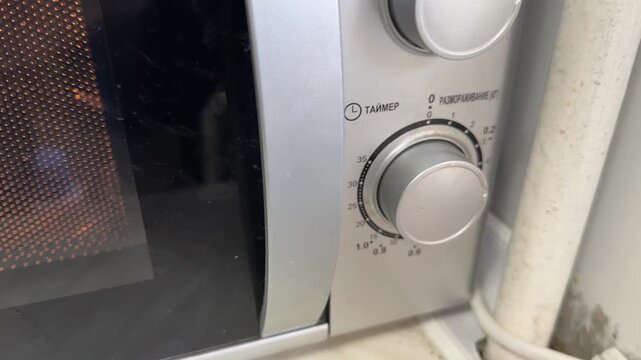 microwave oven control knob and front panel in close up, kitchen appliance interface, home cooking technology concept