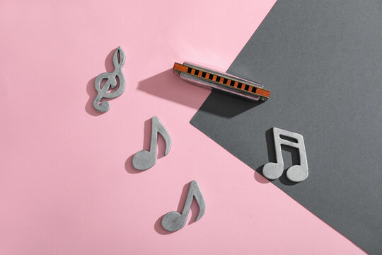 Composition with harmonica and music notes on color background