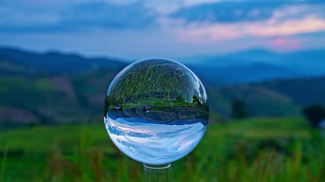 Twilight mountain scenery viewed through a transparent glass sphere, blending abstract refraction effects with natural beauty and calm ambiance.