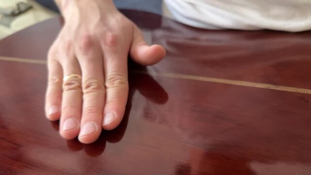 Person hitting acoustic guitar body with palm close up at home, producing strong rhythmic percussion sound, improvised music activity, creative hobby concept