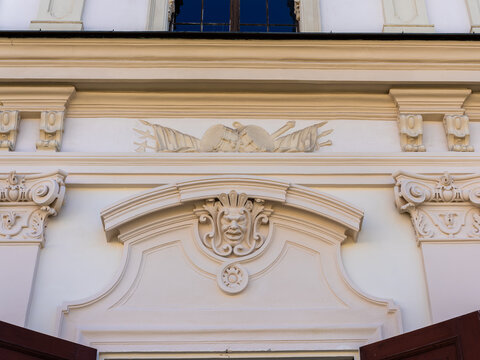 View of the ornate architectural details of Belvedere Palace featuring a grotesque mask relief and military trophy carvings on the white facade in Vienna, Vienna, Austria.