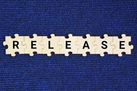 Wooden puzzle with the word Release. to set free, let go, or make something available.