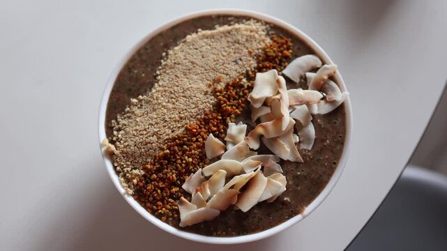 Healthy smoothie bowl with coconut flakes bee pollen and nut topping served on white table nutritious vegan breakfast with natural superfoods