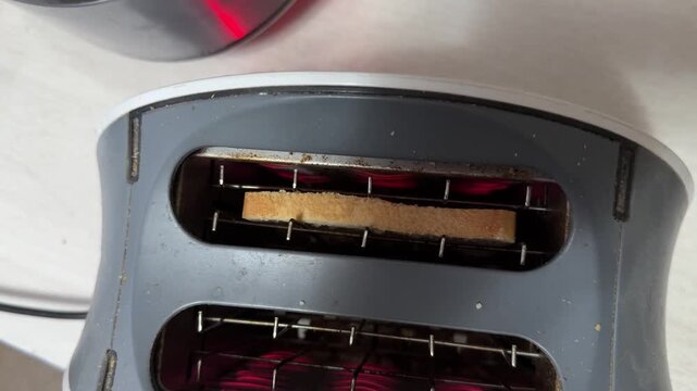 toaster with glowing heating elements preparing bread, kitchen appliance in use, breakfast cooking concept, home lifestyle scene