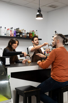 Bar staff serving beer and drinks to a male customer at a modern bar