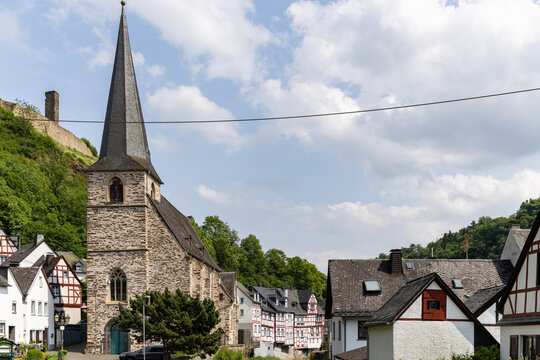 View of the historic Parish Church of the Holy Trinity and traditional half-timbered houses under a blue sky in Monreal, Rhineland-Palatinate, Germany.