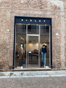 Sisley fashion boutique window display showcasing clothing on mannequins in Fiorenzuola d'Arda, Italy