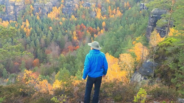man on a lookout above an autumn forest colorful rocky valley