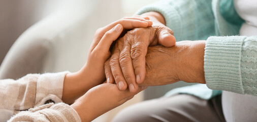Fototapeta na wymiar Senior woman with daughter holding hands at home, closeup