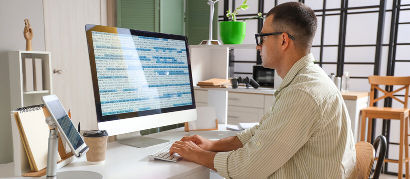Male programmer working with computer at table in office