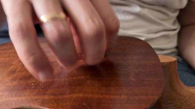 Person tapping fingers on acoustic guitar body close up at home, producing rhythmic percussion sound, improvised music activity, creative hobby concept